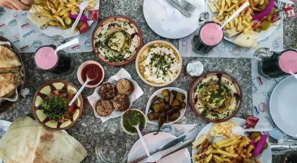 Obfity posiłek w Jordanii: hummus, falafel, frytki, sałatka i napoje. Ceny jedzenia w Jordanii są przystępne.