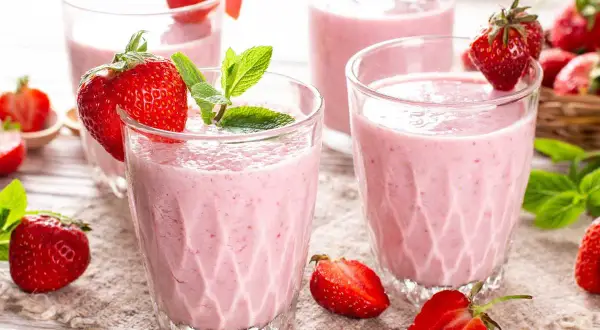 Batidos de fresa en vasos con fresas frescas y hojas de menta.