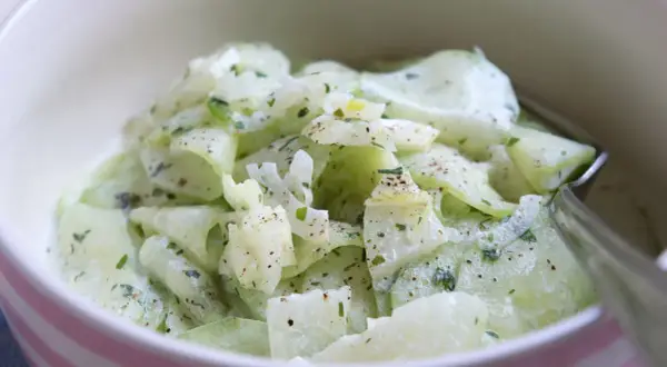 Cremiger Gurkensalat, ein einfaches und erfrischendes gurkensalat rezept, garniert mit Kräutern und Pfeffer.