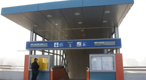 Na dworcu kolejowym mężczyzna sprawdza rozkład jazdy pociągów, szukając połączenia Kraków - Kielce. Peron 3.
