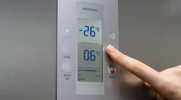 Palec naciska przycisk "super" na panelu zamrażarki, pokazując jaka temperatura w zamrażarce wynosi -26°C.