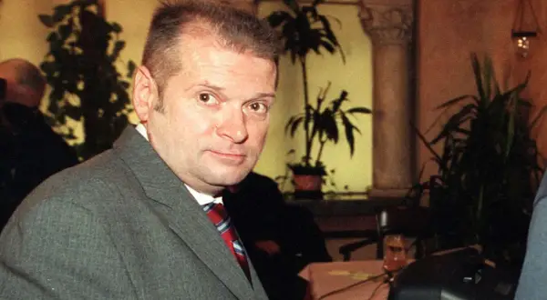 Rutkowski kiedys, w szarym garniturze i czerwonym krawacie, z uwagą patrzy w obiektyw.