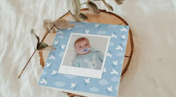 Carte de baptême avec photo d'un bébé, décorée de colombes et de nuages. Parfait pour trouver les mots pour baptême.