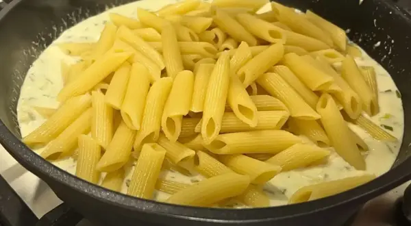 Smażony makaron penne w kremowym sosie z ziołami, gotowy do podania.