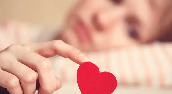 En hand håller ett rött hjärta. Kanske dags för 25 frågor testa din relation?