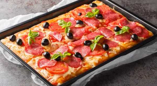 Chrupiąca pizza na cieście francuskim z salami, pomidorami, oliwkami i bazylią, prosto z blachy.