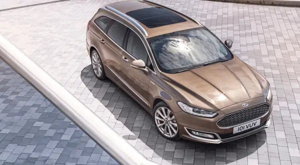 Elegancki, brązowy Ford Vignale kombi z panoramicznym dachem, lśniącym na tle nowoczesnej kostki brukowej.