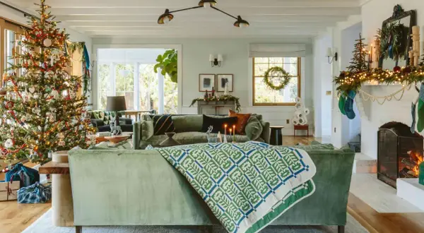 A cozy living room with a decorated Christmas tree, stockings hung by the fireplace, and a festive holiday design.