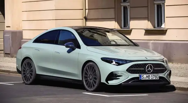 Jasnoszary Mercedes CLA 180 z czarnym dachem stoi na ulicy przed kamienicą.