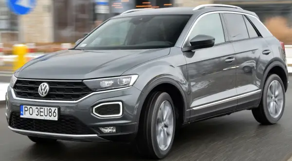 Szary Volkswagen T-Roc w ruchu miejskim. Wiele osób szuka volkswagen t-roc opinie, by podjąć decyzję o zakupie.