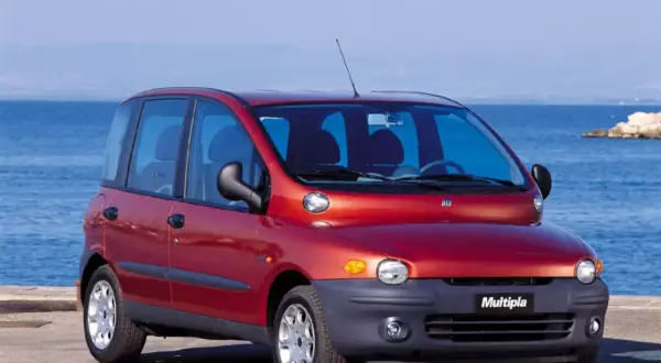 Czerwony Fiat Multipla, często uznawany za najbrzydsze auto na świecie, stoi nad morzem.