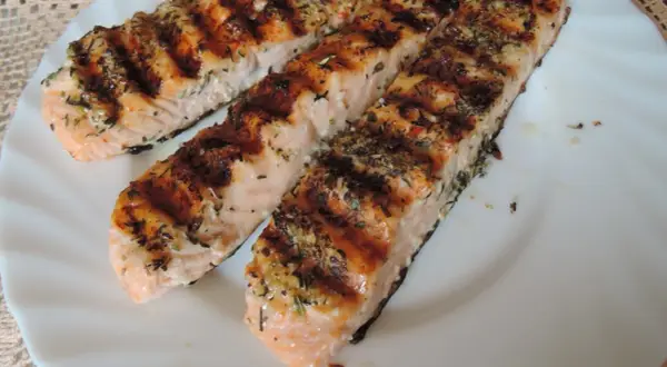 Trzy grillowane filety łososia, przyprawione ziołami, wyglądają apetycznie. Idealna marynata do lososia sprawia, że ryba jest soczysta i aromatyczna.