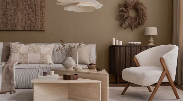 Przytulny salon w stylu naturalnym. Miękka sofa, puszysty fotel i kamienne stoliki tworzą oazę spokoju.