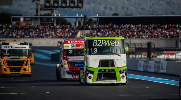 Des camions de course s'affrontent lors du **grand prix camion Castellet**. Le camion n°3, vert et blanc, mène la course devant le n°2 rouge et blanc.