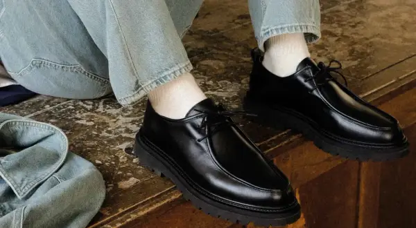 Paire de chaussures noires en cuir synthétique, lacées, avec une semelle épaisse. Parfaites avec un jean décontracté.