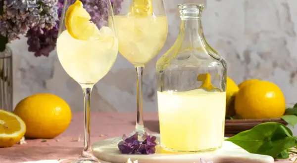 Erfrischender Limoncello Spritz mit Zitronenscheiben, Eis und Flieder.