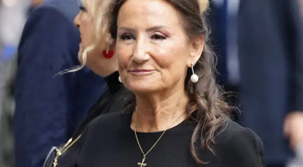 Paloma Rocasolano, con pendientes de perla y un collar con cruz, sonríe con elegancia.