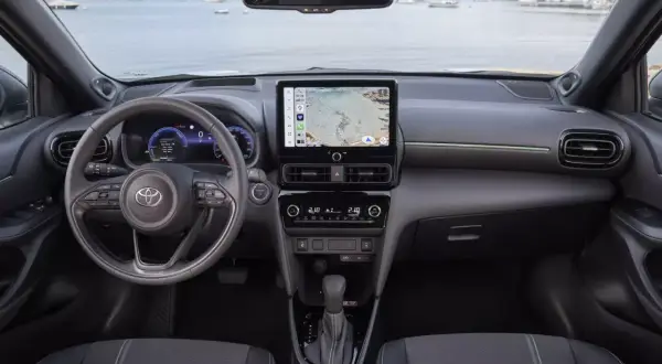 Nowoczesne **toyota yaris cross wnetrze** z ekranem nawigacji i cyfrowymi zegarami. Widok na kierownicę i konsolę środkową.