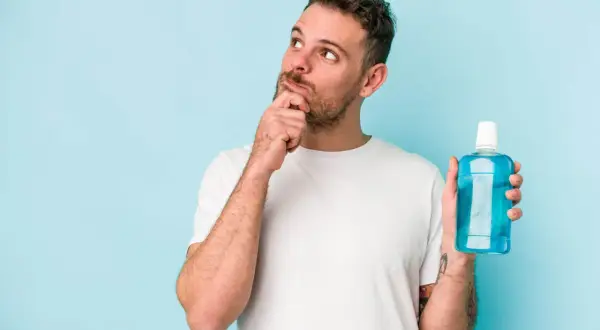 Hombre pensativo con enjuague bucal, ¿será la solución para una infección?