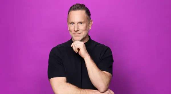 Peter Jihde, med en tankfull blick och handen mot hakan, poserar framför en lila bakgrund.