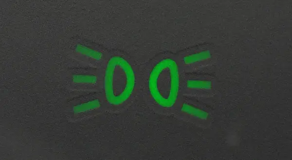 Zielony symbol świateł mijania na ciemnym tle.