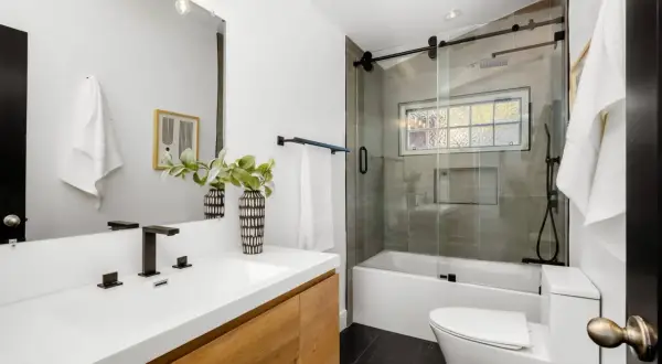 Modernos baños pequeños con lavabo de madera, ducha con mampara de cristal y azulejos grises.