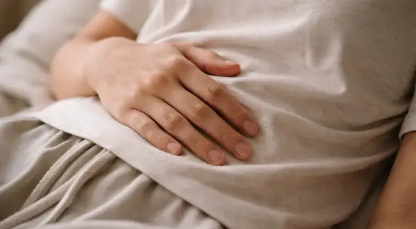 Dłoń na brzuchu, symbolizująca troskę o zdrowie i diagnostykę, np. test ureazowy.