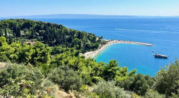 Widok na zatokę z plażą i łodzią. Wspaniałe **Split, Chorwacja atrakcje** przyciągają turystów.