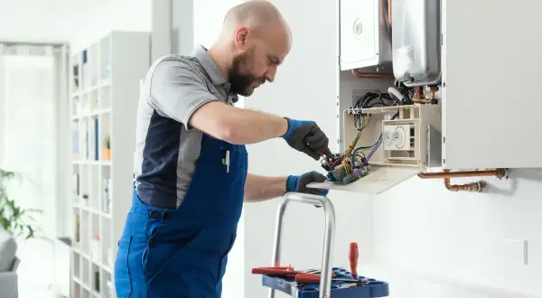 Técnico revisa caldera con presión por debajo de 1 bar. Trabaja en la placa electrónica con herramientas.