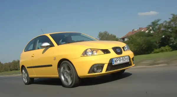 Żółty Seat Ibiza 3 w ruchu, widoczne przednie światła i żarówki.