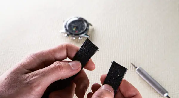 Maintenant, découvrez comment changer un bracelet de montre connectée. Un outil est visible à côté du bracelet noir démonté.