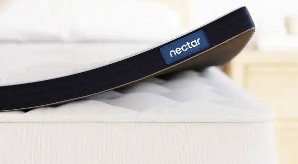 A Nectar mattress topper is shown. While toppers can improve comfort, it's worth considering if a mattress topper can cause back pain if it's too soft or firm for your needs.