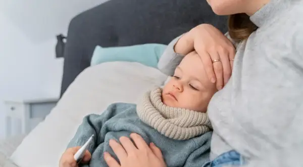 Matka sprawdza temperaturę chorego dziecka, które ma gorączkę.