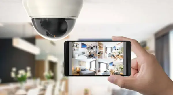 Caméra de surveillance au plafond et smartphone affichant plusieurs flux vidéo, un type d'alarme moderne pour la sécurité domestique.