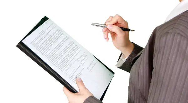 Kobieta w garniturze analizuje dokumenty, przygotowując się do kontroli nadzoru budowlanego.