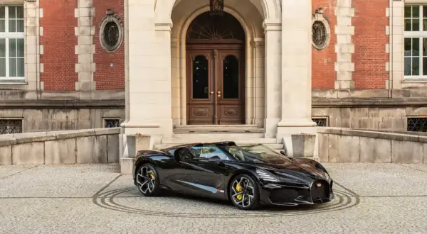Czarny Bugatti przed pałacem. To auto, z jakiego kraju jest Bugatti, symbolizuje francuską elegancję i moc.