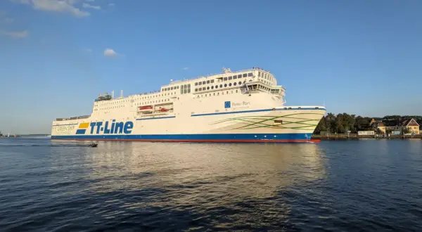Duży biały prom TT-Line "Peter Pan" płynie po wodzie przy słonecznej pogodzie.