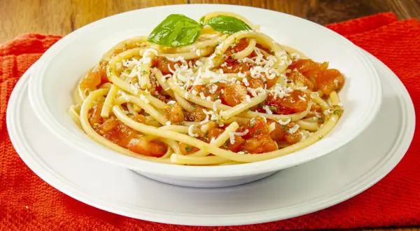 Un piatto invitante di pasta alla carrettiera, con pomodoro fresco, basilico e formaggio grattugiato.