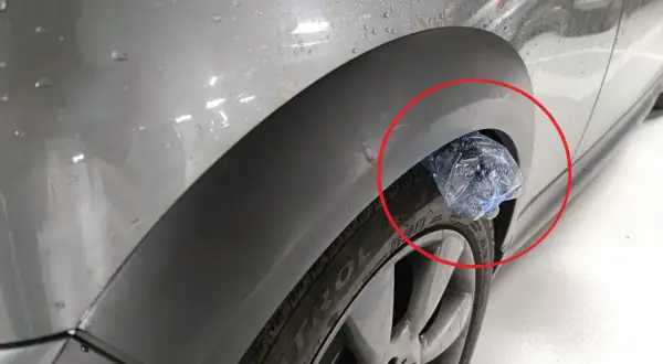 Plastikowa butelka utknęła w nadkole samochodu, tworząc nietypową ozdobę.