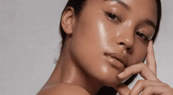 Aha, qué es esa piel radiante y jugosa. Un primer plano de una mujer con un brillo natural en su rostro y cuello.