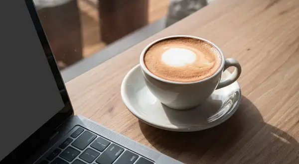 Kawa latte obok laptopa. Idealna przerwa na 8 godzin pracy, by naładować baterie.