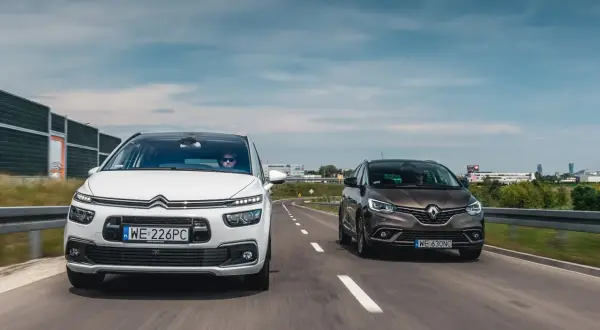 Biały Citroën C4 Grand Picasso i brązowy Renault Scenic jadą obok siebie drogą.