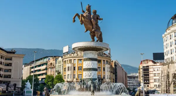 Pomnik Wojownika na koniu w centrum Skopje, stolicy Macedonii, z fontannami i budynkami w tle.