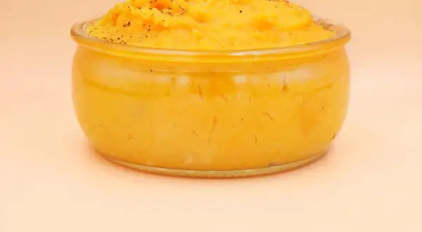 Pyszne, kremowe puree z batata w szklanym naczyniu, posypane świeżo mielonym pieprzem. Idealne jako dodatek do obiadu.