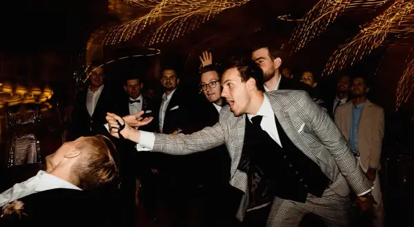 Mężczyzna w kratkę wykonuje sztuczkę, jakby unosił leżącego kolegę. Efekt "shutter widmo" dodaje dynamiki scenie.
