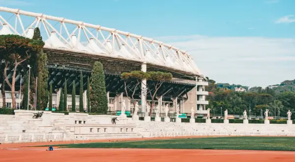 Stadion w Rzymie z rzędami rzeźb i zielenią.