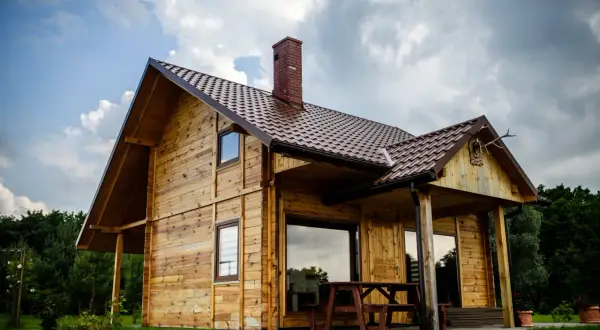 Drewniany domek w zielonej dolinie Czerce, z ceglanym kominem i porośniętym trawą podwórkiem.