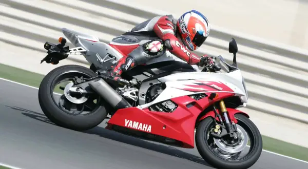 Motocyklista w czerwonym kombinezonie śmiga na torze na czerwono-białej Yamasze R6. Od ilu lat można robić prawo jazdy na motor 600? Od 20.