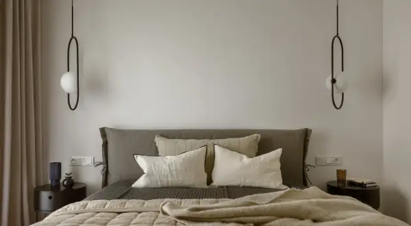 Sypialnia w stylu bauhaus z łóżkiem, poduszkami i minimalistycznymi lampami.
