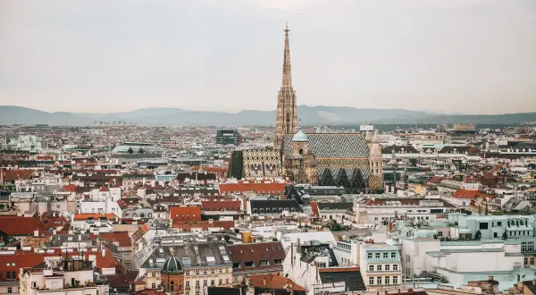 Ein atemberaubender Blick auf Wien von oben. Der Stephansdom mit seinem markanten Turm und dem bunten Dach dominiert die Stadtansicht.